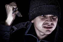 Young angry man with knife on black background